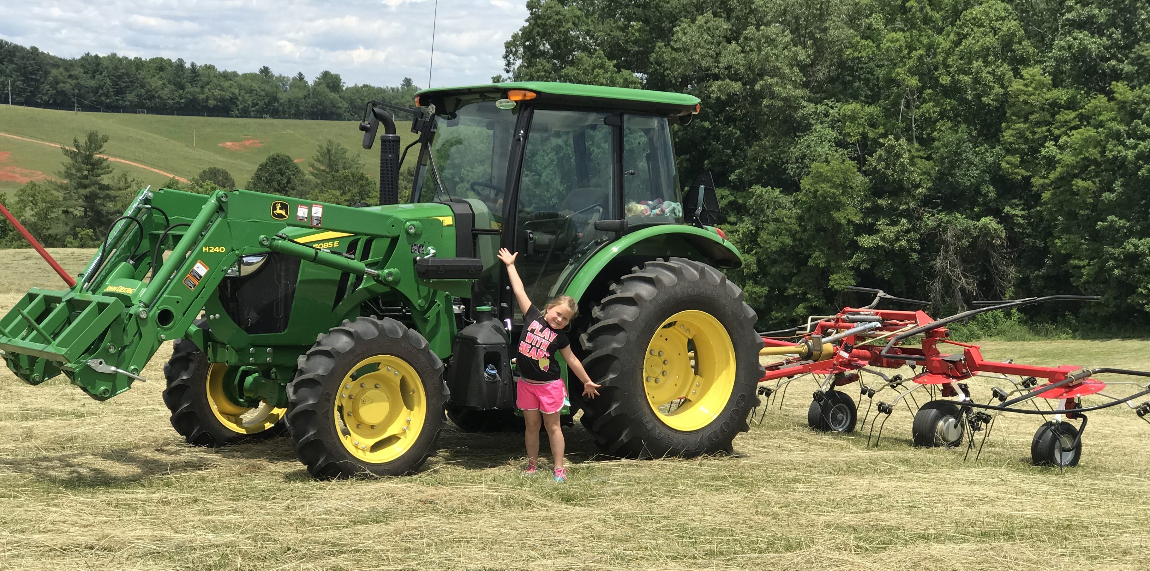 A young girl standing in front of a tractor.