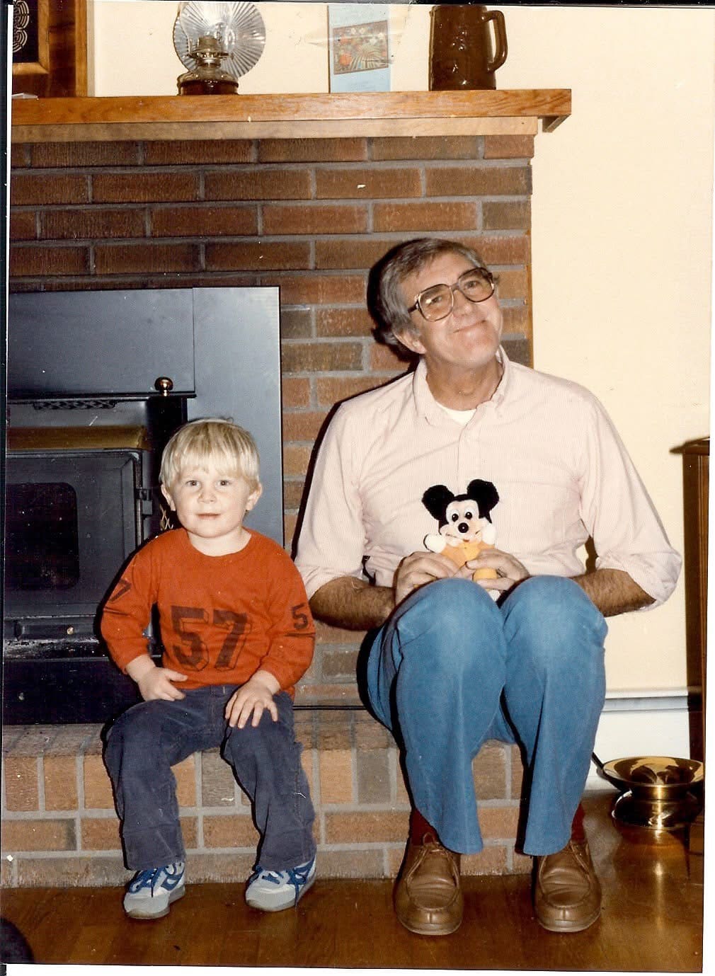 A man and boy sitting in front of a fireplace.
