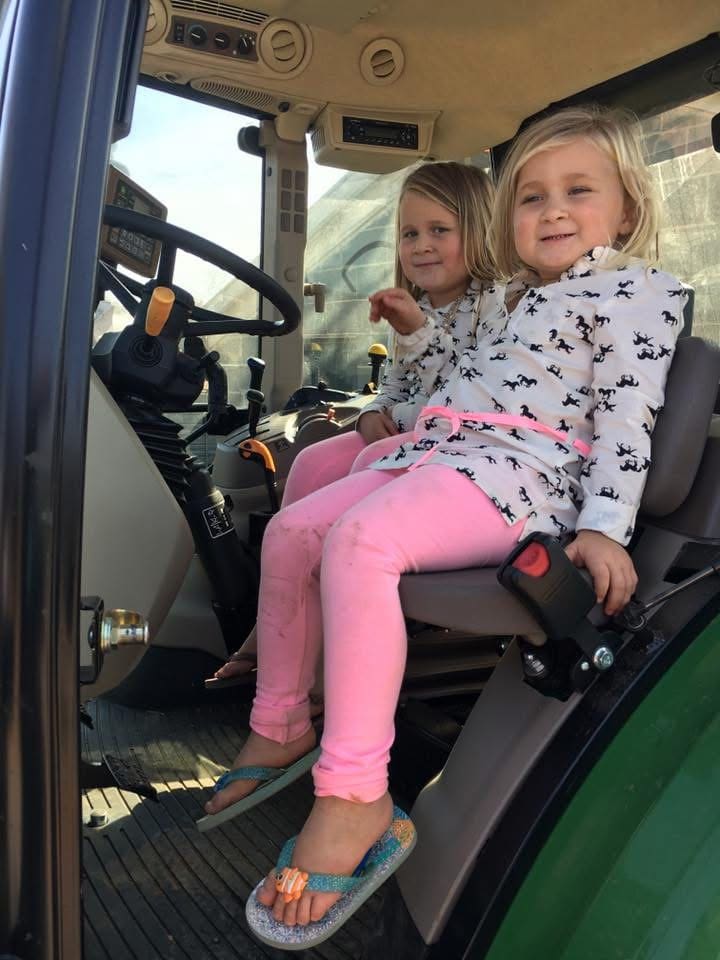 Two girls sitting in a tractor seat