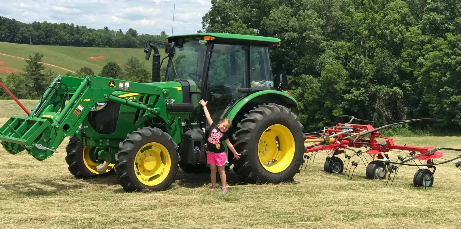 A young girl standing in front of a tractor.